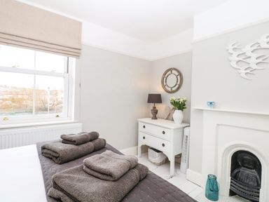 A bedroom with a bed folded towels lamp flowers and a fireplace at Cool Stone Cottage Instow near Bideford