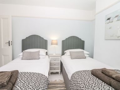 A bedroom with two single beds a nightstand with a lamp in between and folded towels on each bed at Cool Stone Cottage Instow near Bideford
