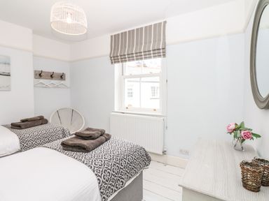 A bedroom with two single beds next to a window and a dresser with flowers at Cool Stone Cottage Instow near Bideford