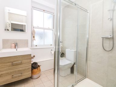 A bathroom with a wooden vanity sink toilet shower with glass door and a window at Cool Stone Cottage Instow near Bideford