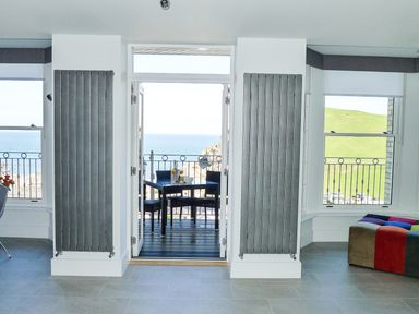 A room with two vertical radiators on either side of a door leading to a balcony with a table and chairs overlooking the sea at 5 Arlington Villas Ilfracombe