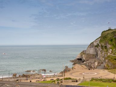 A coastal scene with a rocky shoreline a paved circular area and a cliff with a flag at 5 Arlington Villas in Ilfracombe