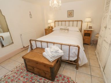 A bedroom with a metal bed frame wooden chest bedside tables and a mirror at Trevoole Barn in Praze An Beeble