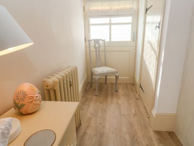 A small hallway with a wooden chair at the back a radiator and a small table with a decorative lamp at Trevoole Barn in Praze An Beeble