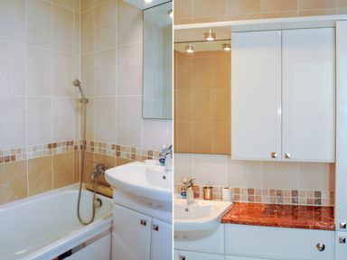 A bathroom with a bathtub and a sink with cabinets and a mirror at Ocean Breeze in Ilfracombe