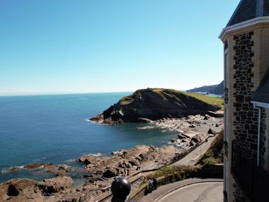 A coastal view with rocky shoreline and ocean next to a building at Ocean Breeze in Ilfracombe