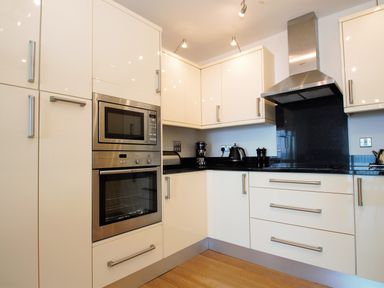 A kitchen with built in microwave and oven white cabinets black countertop and stainless steel range hood at Ocean Breeze in Ilfracombe