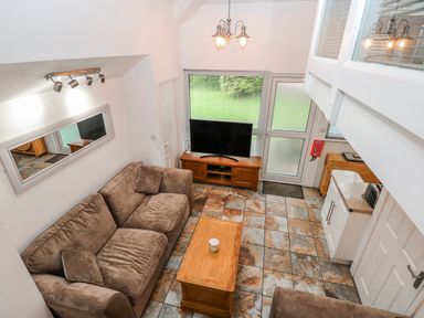 A living room with a sofa and television at Trelessy Lodge near Amroth