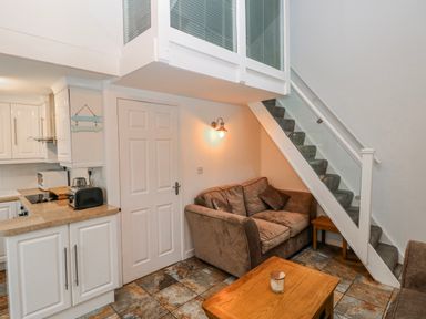A living room with a sofa and staircase at Trelessy Lodge near Llanteg