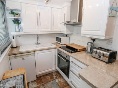 A kitchen with appliances and cabinets at Trelessy Lodge in Llanteg near Amroth