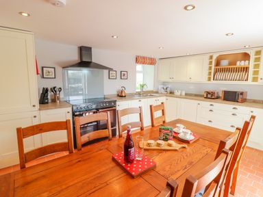 A kitchen with wooden dining table and chairs and cooking appliances at Tai Ucha in Cerrigydrudion