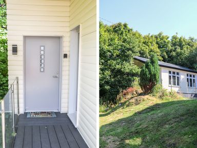 A front door entrance with a welcome mat and a side view of a white house surrounded by trees and greenery at Hidden Gem Cabin in Lettermacaward near Dungloe County Donegal