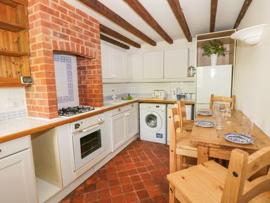 A kitchen with wooden dining table and chairs gas stove washing machine and refrigerator at Blenheim Edge The Causeway in Woodstock