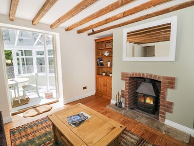 A living room with a wooden coffee table a fireplace and a doorway leading to a sunroom at Blenheim Edge The Causeway in Woodstock