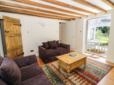 A living room with two sofas a wooden coffee table a patterned rug and a dining area visible through an open door at Blenheim Edge The Causeway Woodstock