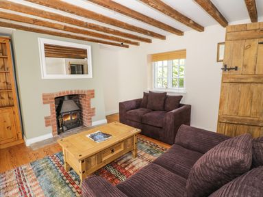 A living room with two sofas a wooden coffee table a fireplace and exposed wooden beams at Blenheim Edge The Causeway in Woodstock