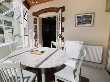 A dining area with a round wooden table and four chairs near a door with glass panels at Blenheim Edge The Causeway in Woodstock