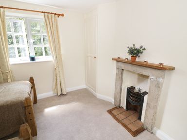 A bedroom with a single bed near a window and a fireplace with a flower pot at Blenheim Edge The Causeway in Woodstock