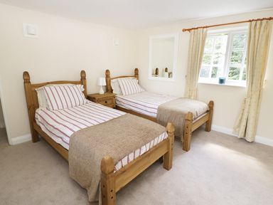 A bedroom with two single beds wooden bedside table lamp and window with curtains at Blenheim Edge The Causeway in Woodstock