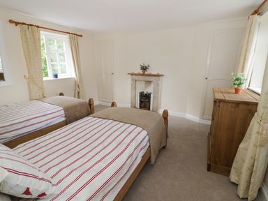 A bedroom with two single beds next to each other a wooden dresser and a small fireplace at Blenheim Edge The Causeway in Woodstock