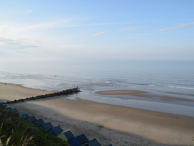 A sandy beach with a wooden groyne and beach huts in front of the sea at 21 Siesta Mar in Mundesley