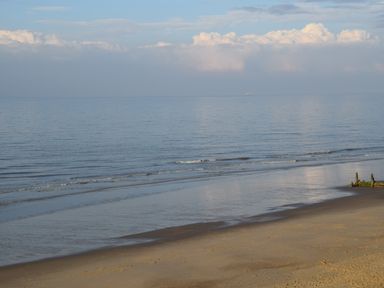 A sandy beach with gentle waves and a cloudy sky at 21 Siesta Mar in Mundesley
