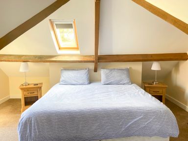 A bedroom with a double bed with two pillows two bedside tables with lamps and a skylight window at The Coach House in Llanrwst