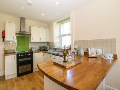 A kitchen with wooden countertops white cabinets and a window at Ty Mawr in Llanddaniel Fab