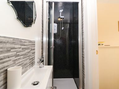 A bathroom with a white sink and a chrome faucet next to a black shower with white speckles at Ty Mawr in Llanddaniel Fab