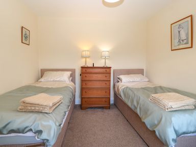 A bedroom with two single beds a wooden chest of drawers and lamps at Ty Mawr in Llanddaniel Fab