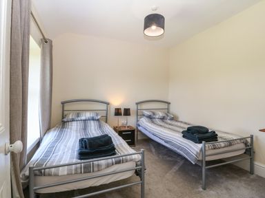 A bedroom with two single beds and a nightstand with lamps at Ty Mawr in Llanddaniel Fab