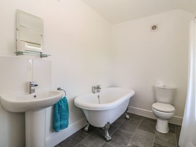 A bathroom with a pedestal sink a clawfoot bathtub a toilet and a turquoise towel at Ty Mawr in Llanddaniel Fab