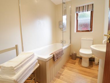 A bathroom with a bathtub shower toilet sink and stacked towels at The Alders in Llanfyllin