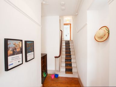 A hallway with framed pictures on the wall wooden floor stairs with a black runner and a hat hanging on the wall at Star House in Marazion