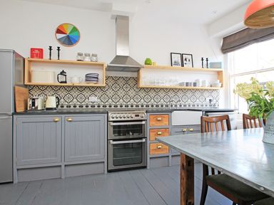 A kitchen with grey cabinets stove and patterned tile backsplash at Star House in Marazion