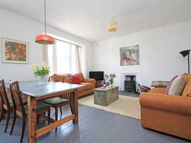 A living room with two brown sofas a wooden dining table with four chairs and a wood stove at Star House in Marazion