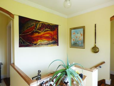A hallway with a large plant on a wooden railing and two paintings on yellow walls at Maifield in Carrick-On-Suir County Tipperary