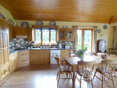 A kitchen with wooden cabinets a dining table with chairs and flowers a jukebox at Maifield in Carrick-On-Suir County Tipperary