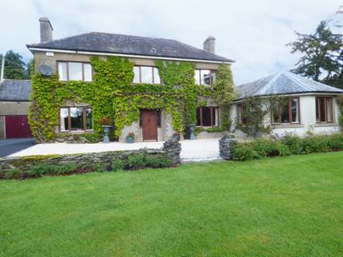 A stone house with ivy on the walls and multiple windows in a garden at Maifield in Carrick-On-Suir County Tipperary