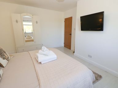 A bedroom with a bed and wardrobe at Blacksmiths Cottage in Shilbottle