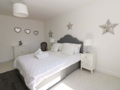 A bedroom with a bed and nightstands at Blacksmiths Cottage in Shilbottle
