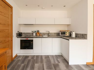 A kitchen with white cabinets a microwave toaster kettle and sink at No1 The Lodge in Acton near Bishop's Castle