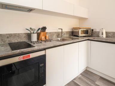 A kitchen corner with a stove, sink, microwave, toaster, knife block and cooking utensils at No1 The Lodge in Acton near Bishop's Castle