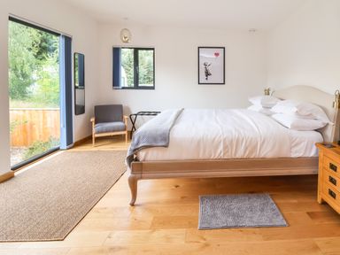 A bedroom with a bed pillow and blanket near a gray armchair and wooden nightstand at No1 The Lodge Acton near Bishops Castle