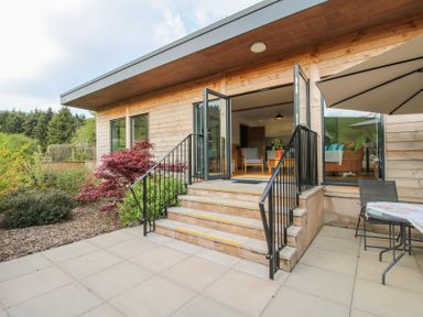 An outdoor patio with stairs leading to an open room with chairs and a table at No1 The Lodge in Acton near Bishops Castle