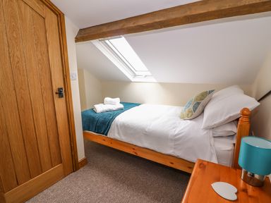A bedroom with a single bed under a skylight window and a wooden door at Pentre Fach in Llandrindod Wells
