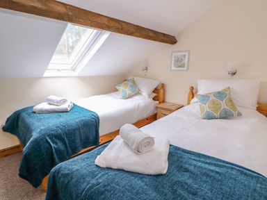 A bedroom with two single beds under a skylight window with blue blankets and folded white towels at Pentre Fach in Llandrindod Wells