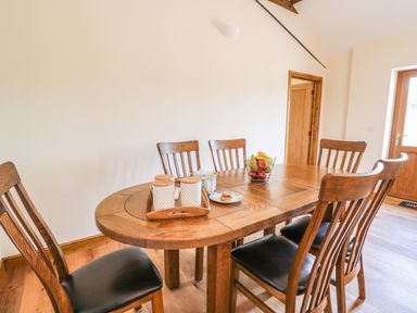 A dining room with a wooden dining table and six chairs a bowl of fruit and containers on the table at Pentre Fach in Llandrindod Wells