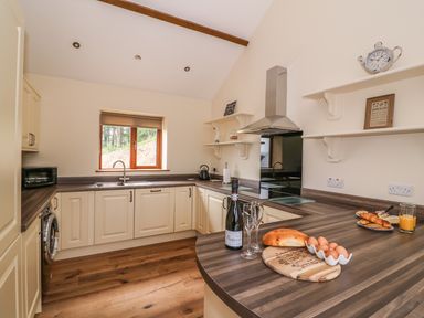 A kitchen with cream cabinets wooden countertops a window and various kitchen items at Pentre Fach in Llandrindod Wells