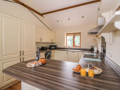 A kitchen with cream cabinets a wooden countertop and breakfast items including orange juice eggs and bread at Pentre Fach in Llandrindod Wells